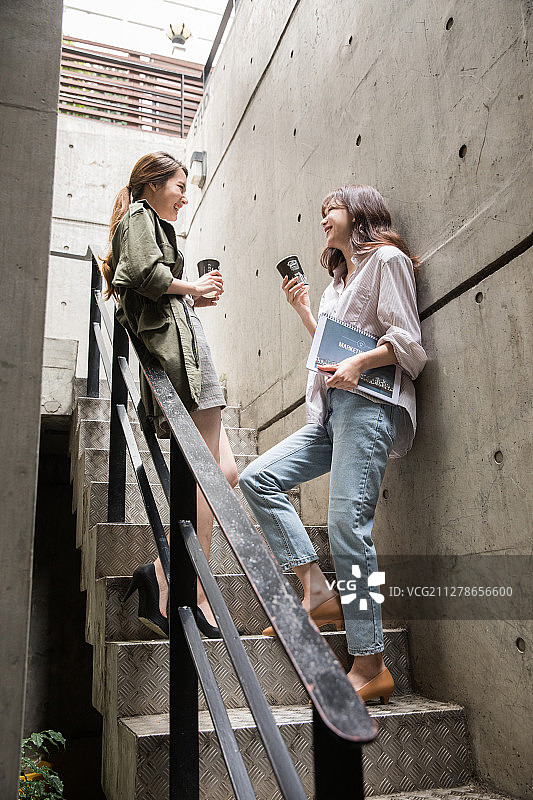 两名同事站在楼梯上喝咖啡聊天的照片图片素材