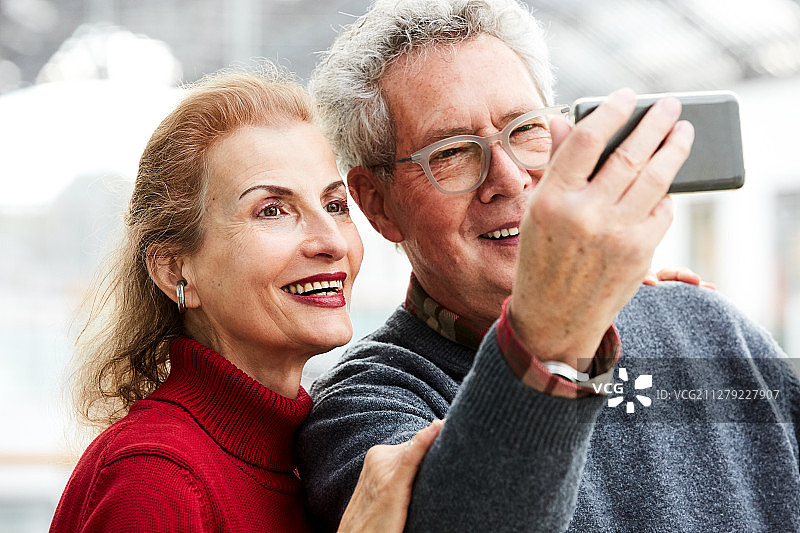 两个快乐的老年人用智能手机自拍的肖像图片素材
