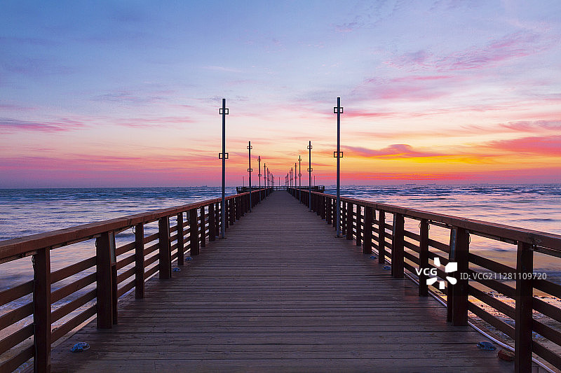 站在桥上拍摄黎明中的海边栈桥图片素材