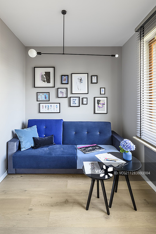 灰色墙壁的狭小客厅里有蓝色的沙发和边桌图片素材