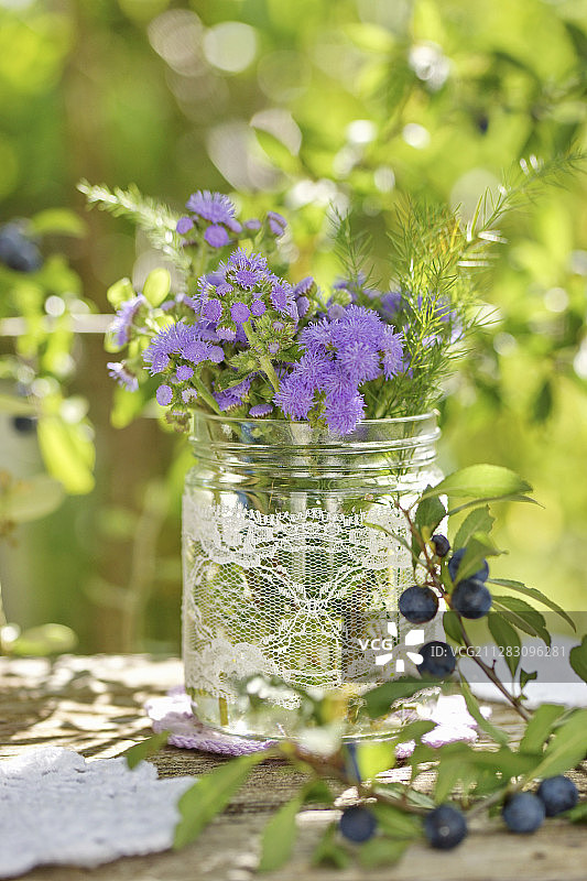 夏末的花束与蓝色的山羊草在玻璃罐，花边装饰图片素材