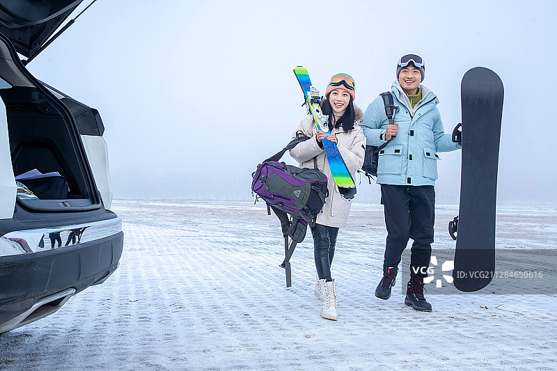 停车场上青年伴侣拿着滑雪板图片素材