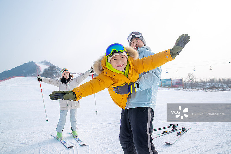 滑雪场上抱着儿子飞的父亲和滑雪的母亲图片素材