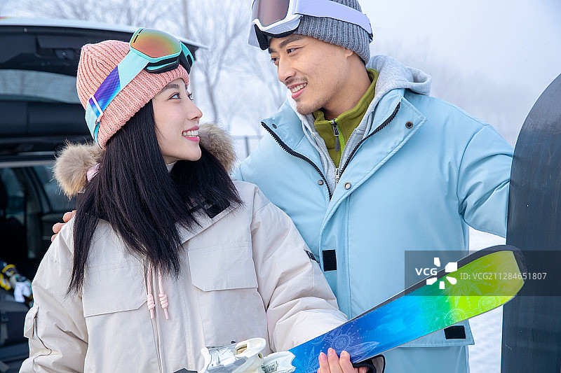 快乐的青年伴侣拿着滑雪板搂在一起图片素材
