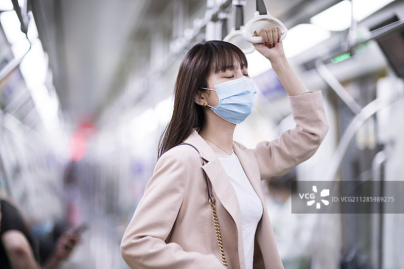 年轻女子戴着防护口罩乘坐地铁图片素材