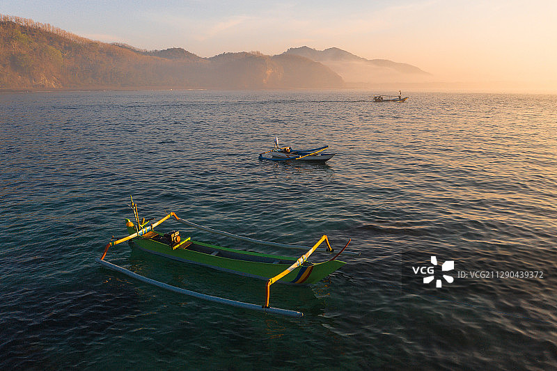 日出时航拍海岛和海岸线上停靠的渔船图片素材