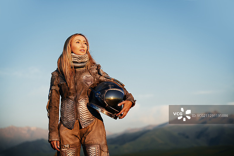 在着陆后，穿着宇航服的女宇航员拿着头盔图片素材
