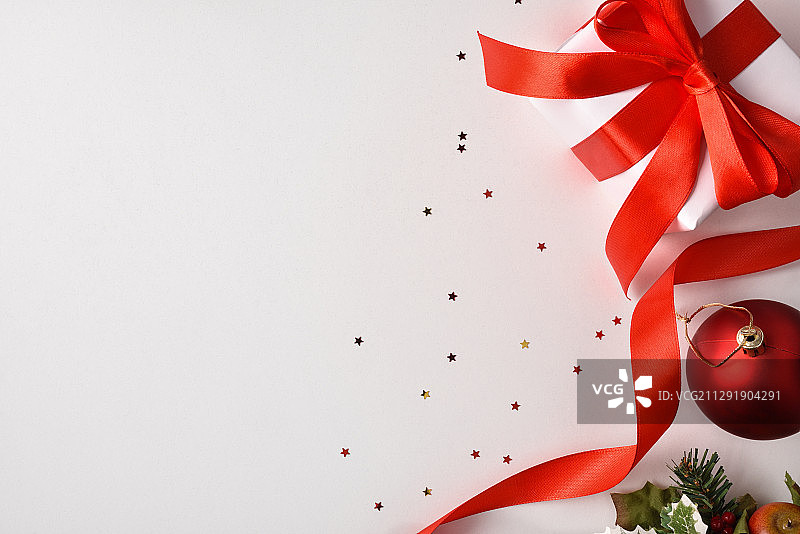 白色的圣诞礼物，红色的蝴蝶结在白色的桌子上，旁边是红色的球图片素材