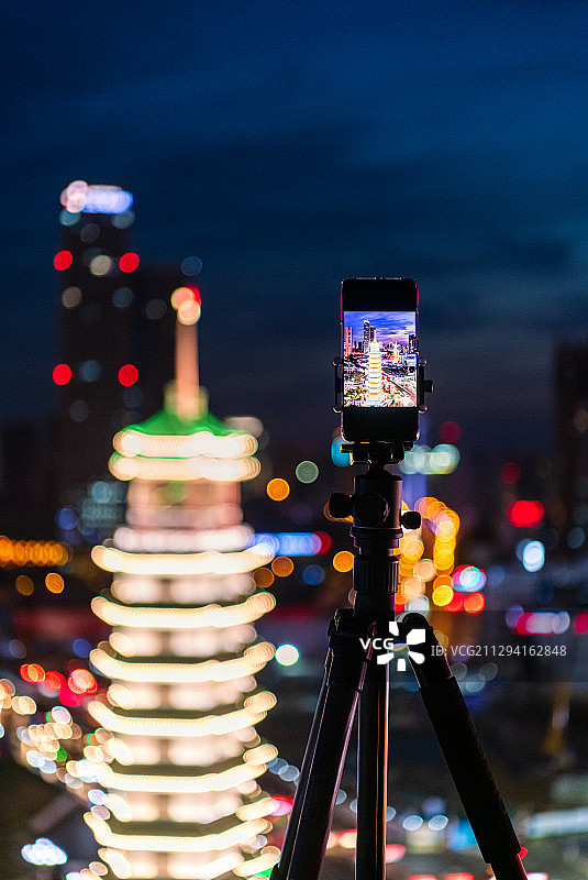 夜晚在三脚架上的手机摄影拍摄城市天际线夜景图片素材