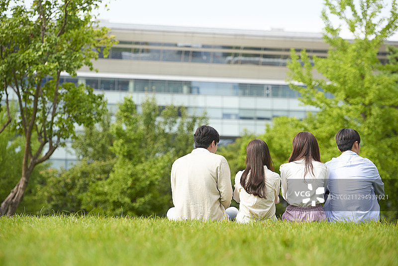 四个大学生并排坐在草地上图片素材