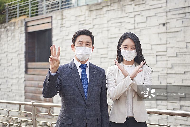 商人和妇女戴着污染口罩站在户外，手举3号和X号的牌子图片素材
