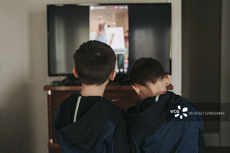 两个男孩在家里通过电视看老师的后视图，莉娜，美国图片素材