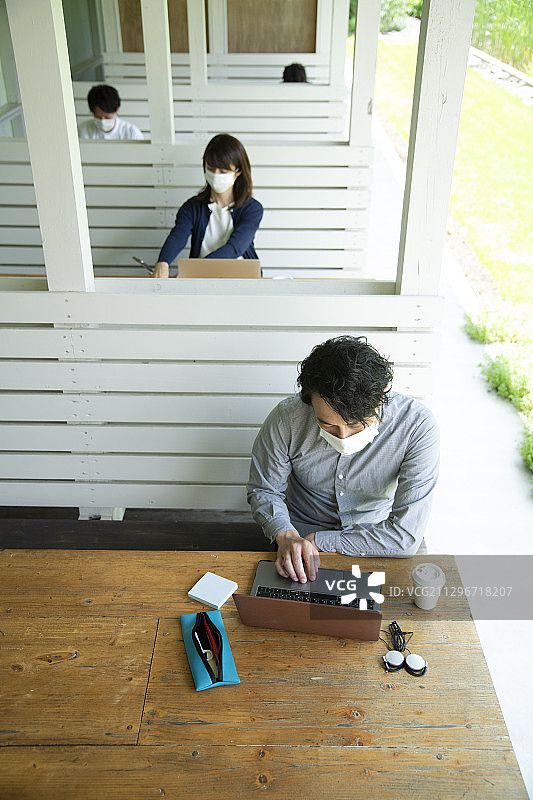 男性和女性正在打造一种户外办公室，将社交距离设置为新常态的办公室风格图片素材