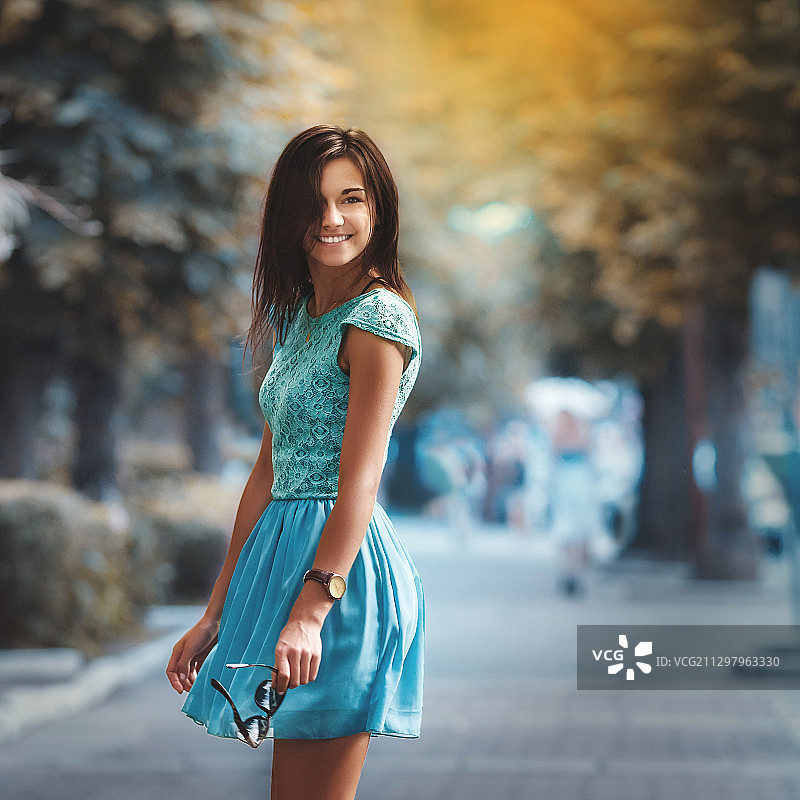微笑的年轻女子站在路上的肖像图片素材