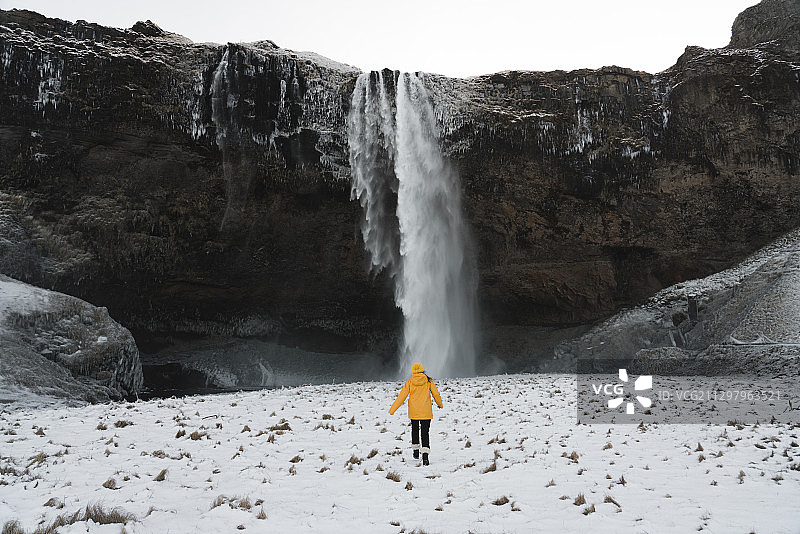 冰岛阿库雷里，女人站在瀑布前的后视图图片素材