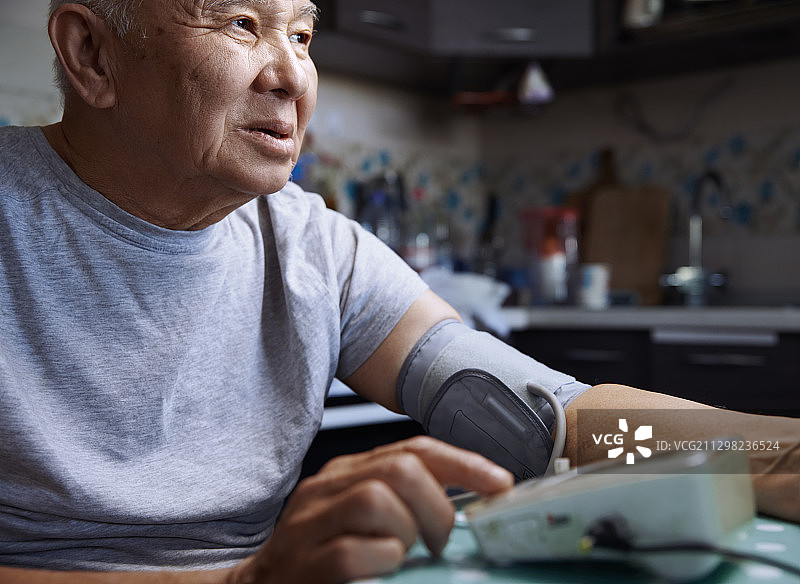 老人在家里用数字血压计测量自己的血压图片素材
