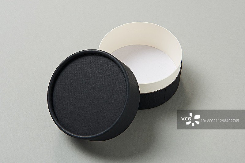 黑色圆形硬纸盒，有单独的盖子，灰色背景图片素材