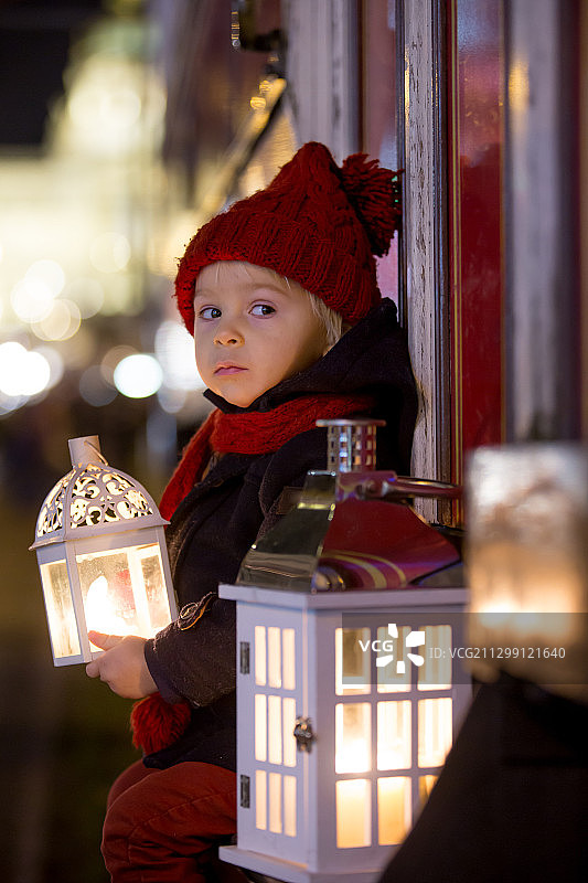 圣诞节期间，一个男孩提着灯笼站在城市里图片素材