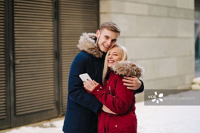 幸福的夫妇在温暖的衣服站在白雪覆盖的街道肖像图片素材