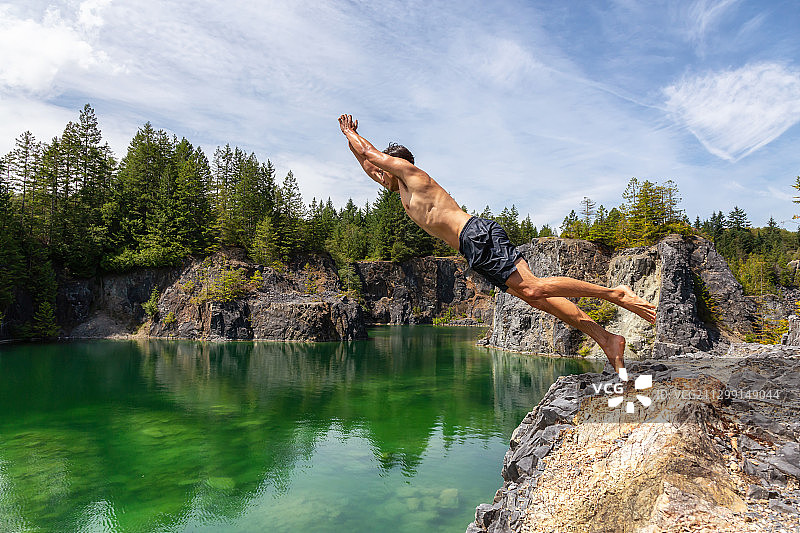 运动和冒险的男人是悬崖跳进一个绿色的湖图片素材