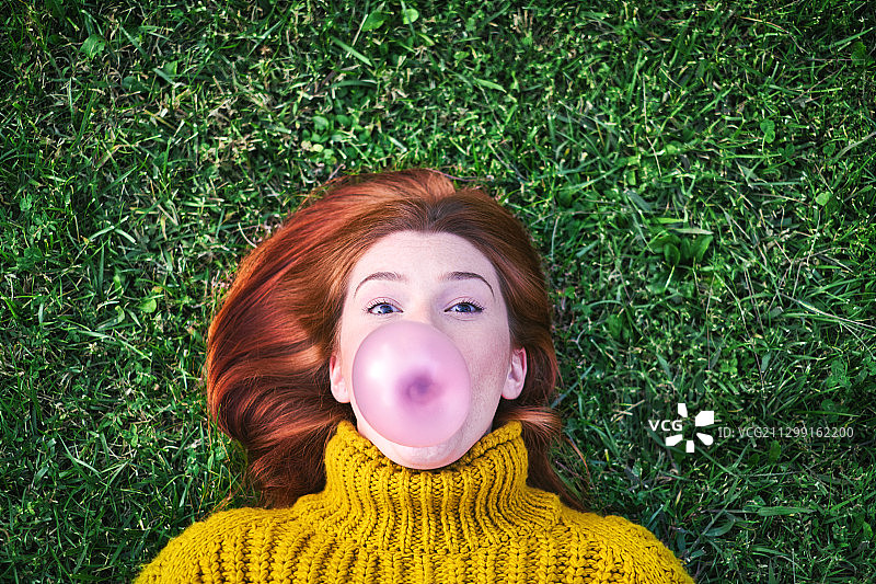 上图是一个女人在草地上吹泡泡图片素材