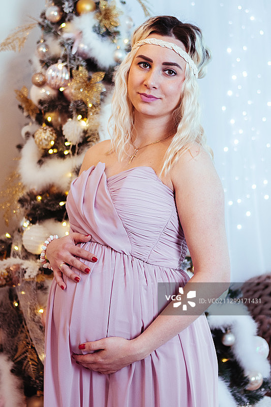 一位优雅的孕妇站在装饰圣诞树旁，波尔塔瓦，乌克兰图片素材