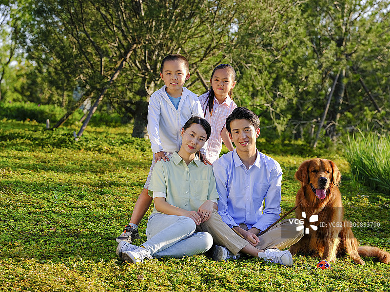 快乐的四口之家和宠物狗在公园合影图片素材