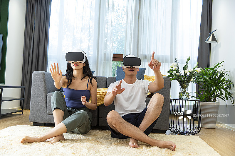年轻情侣在客厅戴着VR眼镜玩游戏图片素材