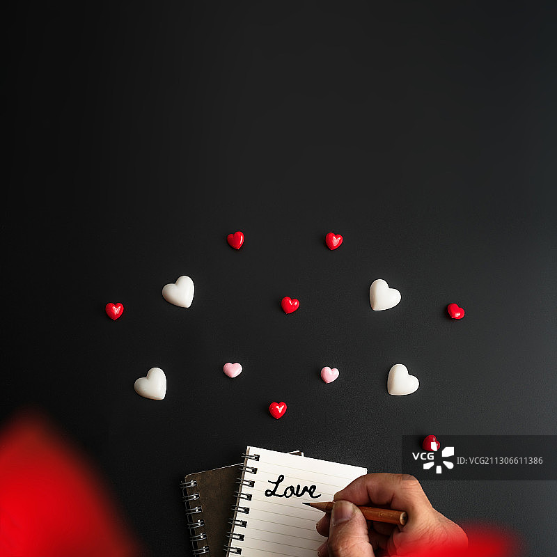 白色和红色的心用手在笔记本上写下爱的文字图片素材