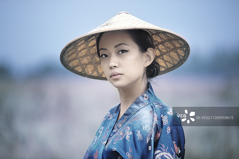 这位年轻的亚洲女子的肖像，穿着传统服饰，戴着草帽图片素材