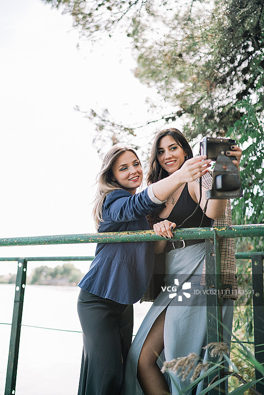 两个白人女性朋友在户外一起拍照与旧电影相机，西班牙图片素材