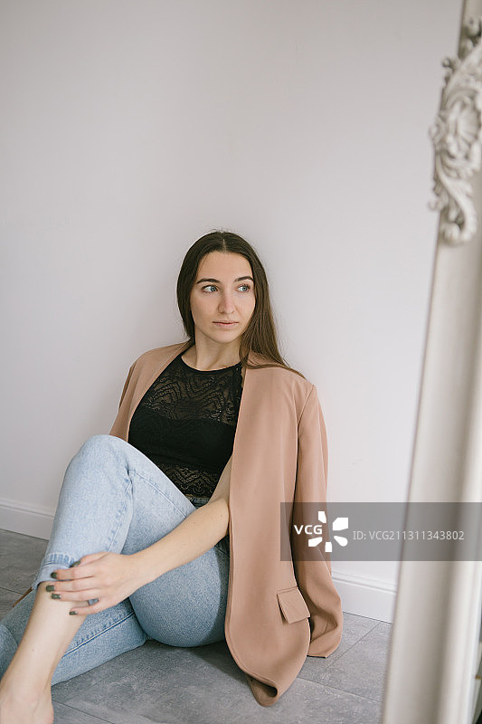 俄罗斯，一名穿着夹克的年轻女子坐在工作室的地板上图片素材