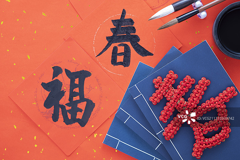 ,中国春节春联上摆放着春字中国结书和毛笔砚台图片素材