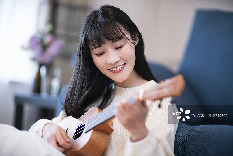 年轻女士在家弹奏吉他图片素材
