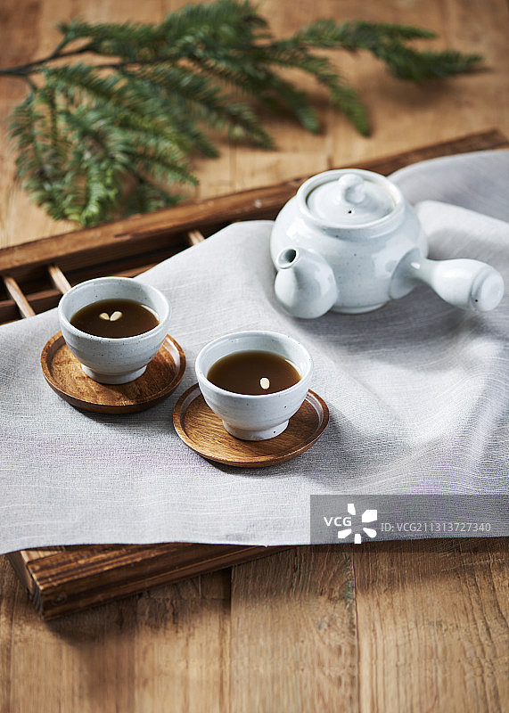 两杯传统的松子茶，旁边是铺着布的木地板茶壶图片素材