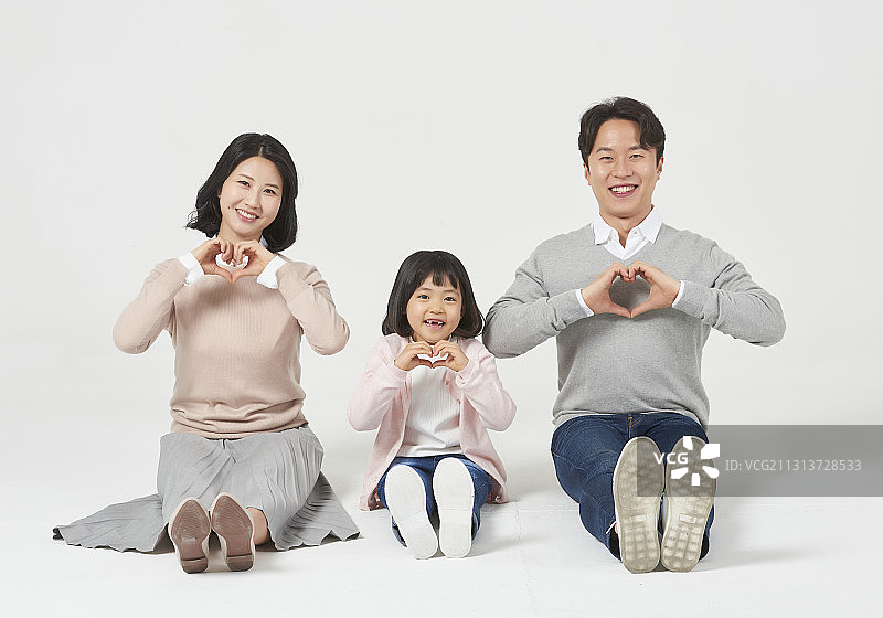 三名家庭成员微笑着坐在白色背景上做心形标志图片素材