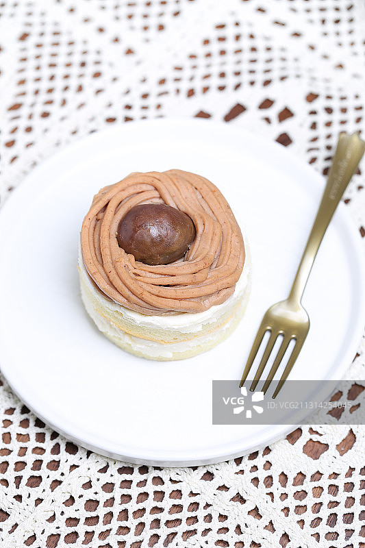 一个放在蕾丝桌布上的奶油栗子蛋糕图片素材