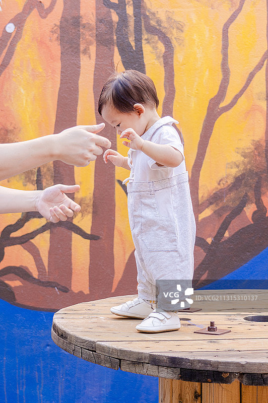 艺术墙前木圆盘上玩的男婴图片素材