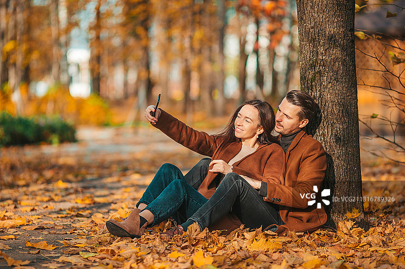 快乐的一家人在阳光明媚的秋天公园散步图片素材