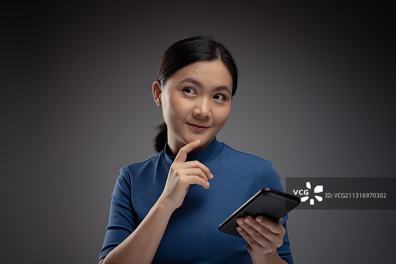 微笑的年轻女商人在灰色背景下使用数码平板电脑的肖像图片素材