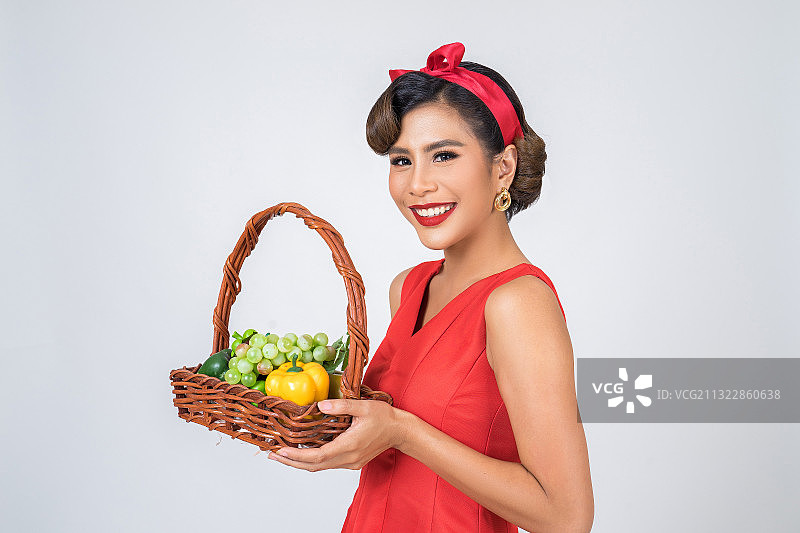 女人的肖像拿着水果在篮子在白色的背景图片素材