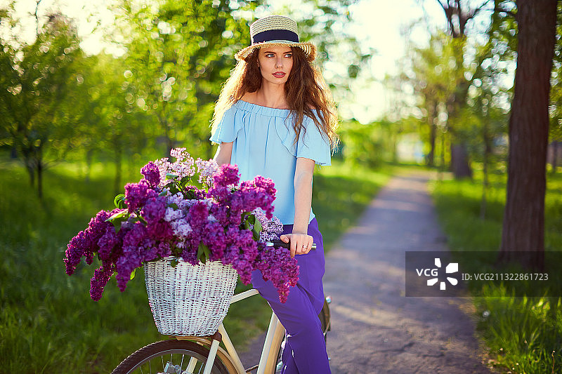 一个快乐美丽的女人的肖像戴着草帽和老式自行车图片素材