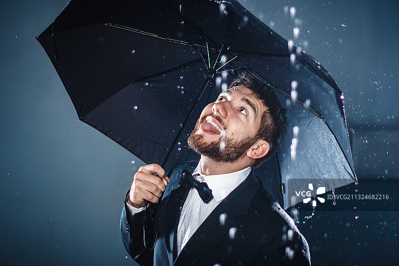 微笑的男人撑着伞站在雨中图片素材