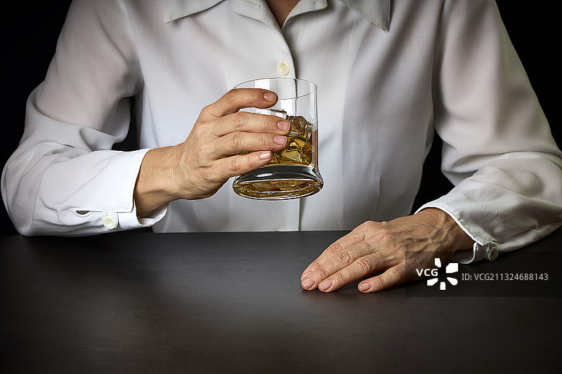 西班牙，一名女子手持一杯加冰的苏格兰威士忌图片素材