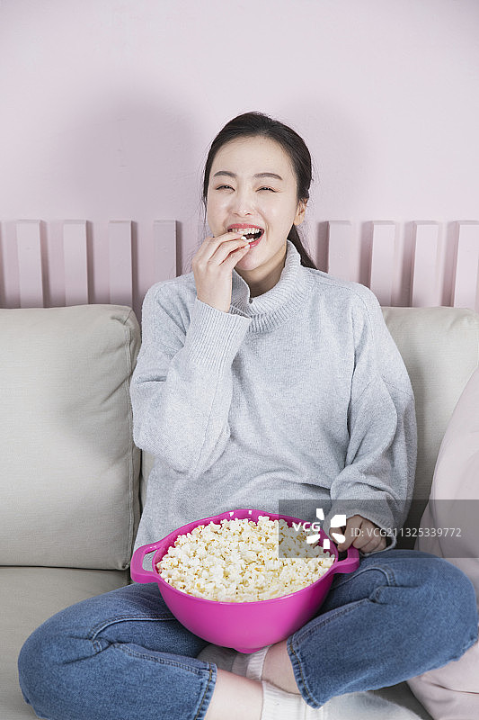 单身女性独自生活的概念是看电视，看电影，吃爆米花图片素材