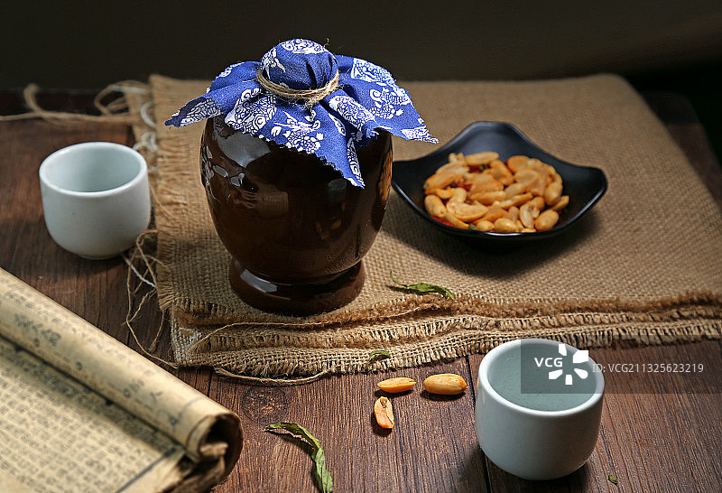 复古酒瓶和酒杯花生米放在木桌上图片素材