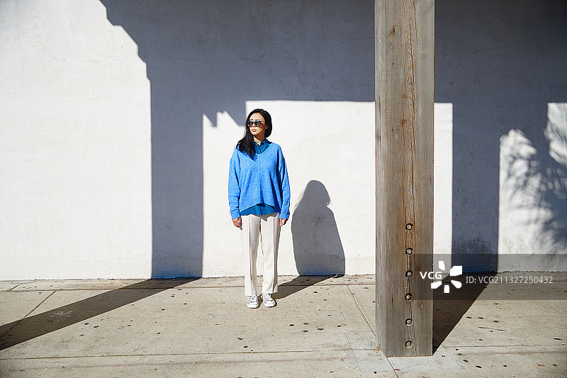 深褐色的女人穿着蓝色的毛衣和白色的裤子探索城市图片素材