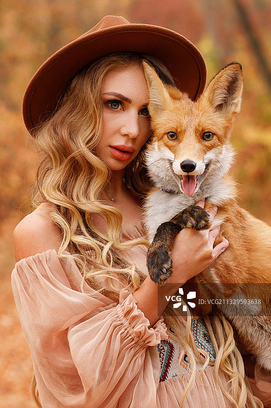 戴着帽子的模特和一只狐狸在秋天图片素材