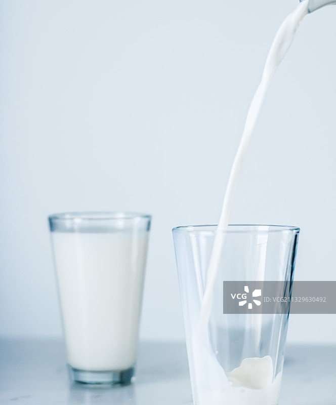 牛奶的特写，牛奶倒在饮用玻璃上的桌子图片素材