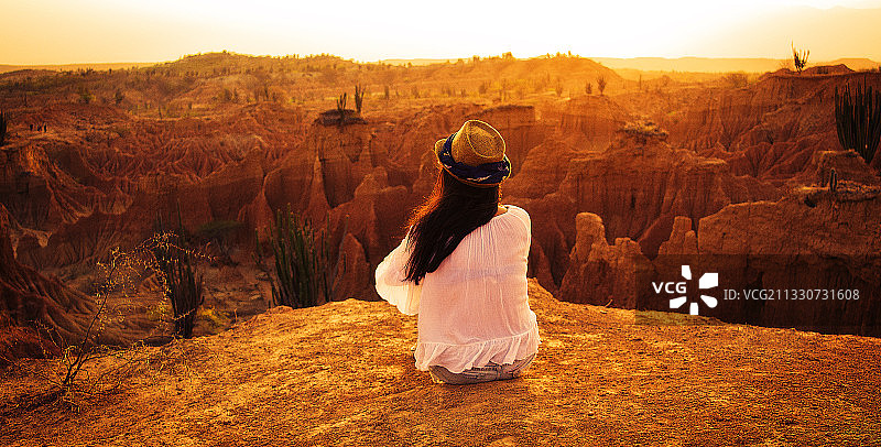 后视图的女人坐在岩石形成的沙漠，维拉维耶加，哥伦比亚图片素材